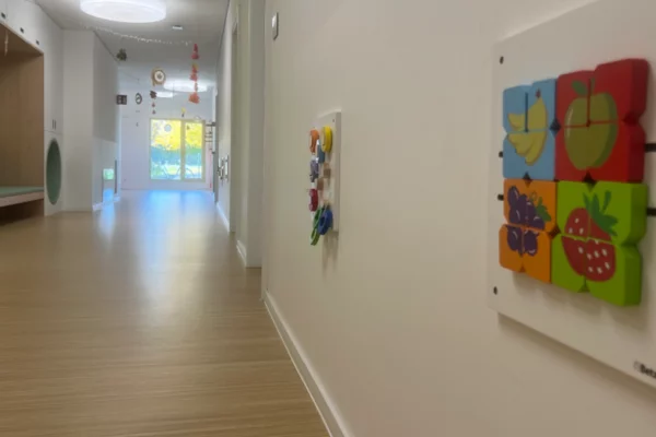 Es wird der Spielflur der Kinderkrippe Villa Regenbogen II gezeigt, mit Motorikspielen an der Wand.