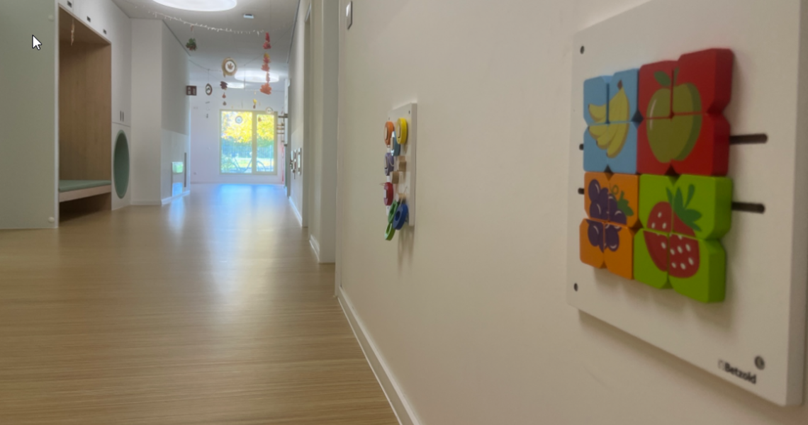 Es wird der Spielflur der Kinderkrippe Villa Regenbogen II gezeigt, mit Motorikspielen an der Wand.