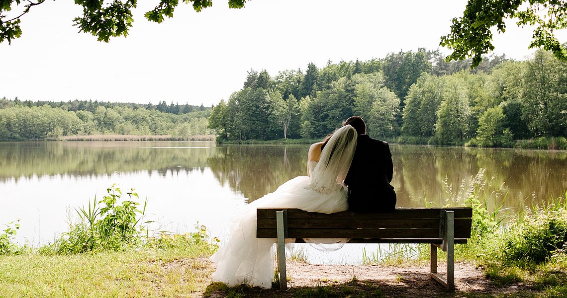 Ein Brautpaar sitzt auf einer Bank und hält sich an den Händen