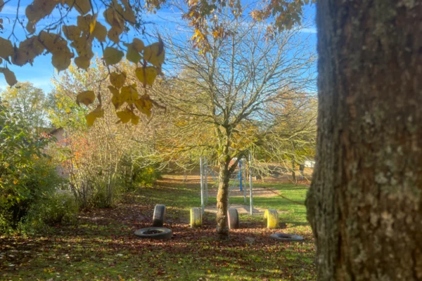 Herbstlicher Garten der Kita Villa Regenbogen I mit großen Autoreifen zum balancieren.