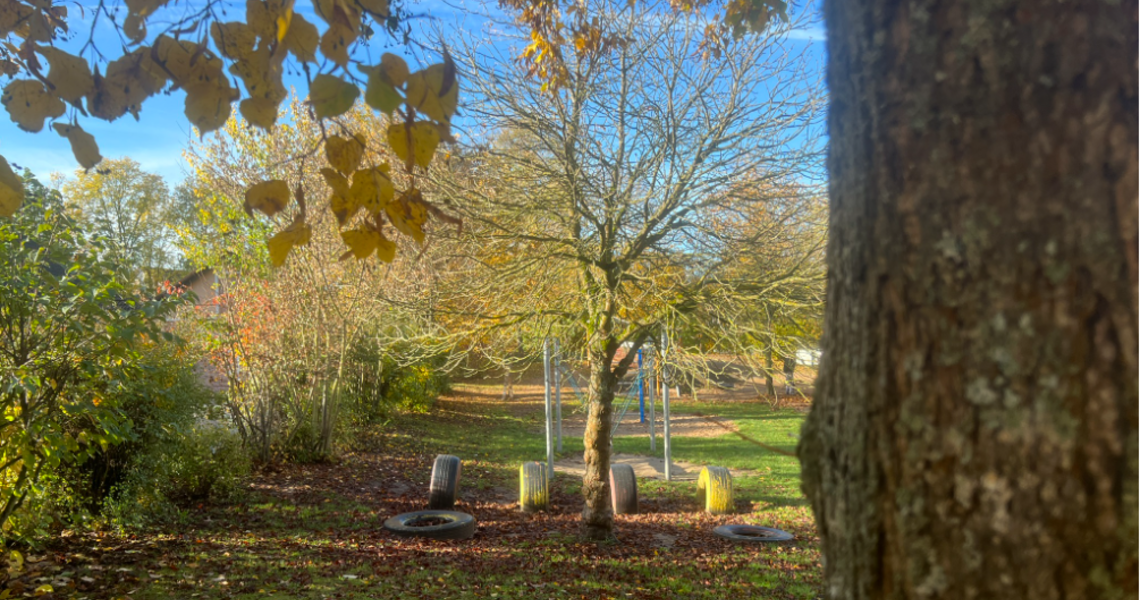 Herbstlicher Garten der Kita Villa Regenbogen I mit großen Autoreifen zum balancieren.
